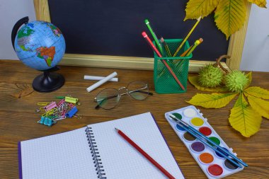 Okul konseptine geri dönelim. Sarı kestane yaprakları ile bir tahta arka plan üzerinde ahşap bir masa üzerinde Okul malzemeleri.