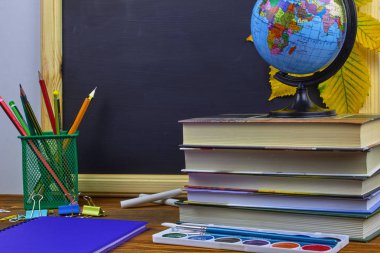 Okul konseptine geri dönelim. Okul malzemeleri ve kitaplar sarı kestane yaprakları ile bir tahta arka plan üzerinde ahşap bir masa üzerinde.