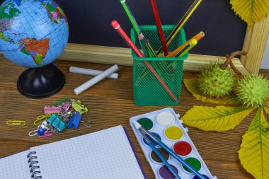 Okul konseptine geri dönelim. Sarı kestane yaprakları ile bir tahta arka plan üzerinde ahşap bir masa üzerinde Okul malzemeleri.