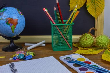 Okul konseptine geri dönelim. Sarı kestane yaprakları ile bir tahta arka plan üzerinde ahşap bir masa üzerinde Okul malzemeleri.
