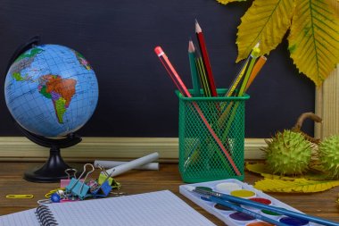 Okul konseptine geri dönelim. Sarı kestane yaprakları ile bir tahta arka plan üzerinde ahşap bir masa üzerinde Okul malzemeleri.