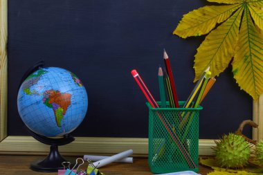 Okul konseptine geri dönelim. Sarı kestane yaprakları ile bir tahta arka plan üzerinde ahşap bir masa üzerinde Okul malzemeleri.