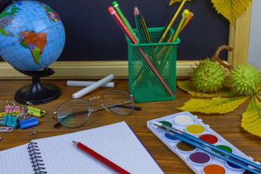 Okul konseptine geri dönelim. Sarı kestane yaprakları ile bir tahta arka plan üzerinde ahşap bir masa üzerinde Okul malzemeleri.