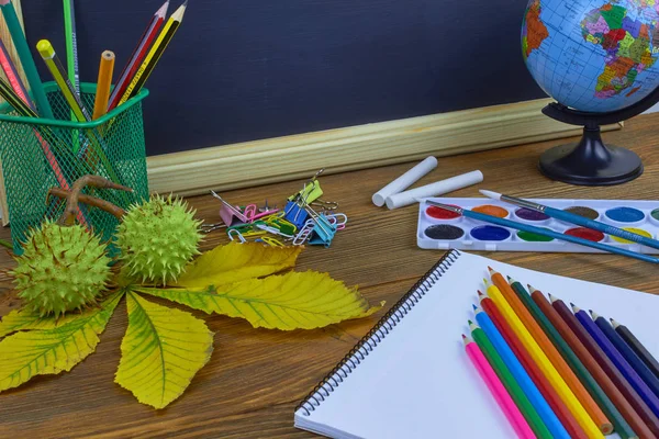 Okul konseptine geri dönelim. Sarı kestane yaprakları ile bir tahta arka plan üzerinde ahşap bir masa üzerinde Okul malzemeleri.