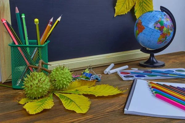 Okul konseptine geri dönelim. Sarı kestane yaprakları ile bir tahta arka plan üzerinde ahşap bir masa üzerinde Okul malzemeleri.