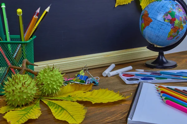 Okul konseptine geri dönelim. Sarı kestane yaprakları ile bir tahta arka plan üzerinde ahşap bir masa üzerinde Okul malzemeleri.