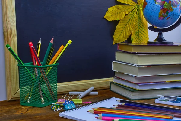 Okul konseptine geri dönelim. Okul malzemeleri ve kitaplar sarı kestane yaprakları ile bir tahta arka plan üzerinde ahşap bir masa üzerinde.