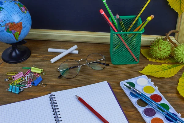 Okul konseptine geri dönelim. Sarı kestane yaprakları ile bir tahta arka plan üzerinde ahşap bir masa üzerinde Okul malzemeleri.