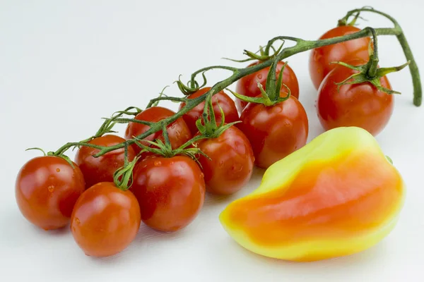 Su damlalı kırmızı kiraz domatesleri ve beyaz arka planda izole edilmiş sarı tatlı biber. Görüntüyü kapat — Stok fotoğraf