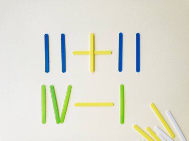 Açık sarı arka plan üzerinde saymak için öğrenme için matematiksel işlemleri hesaplamak için renkli sayma sopalar. Okula dönüş konsepti, davet kartı