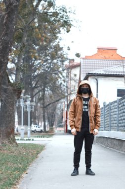 Şehir caddesinde siyah maskeli şık bir genç. Coronavirus karantina durumu. Salgın sırasında sokak tarzı. Tıbbi solunum cihazını pandemik giysi malzemesi olarak kullanacağız. Salgın yaşam tarzı