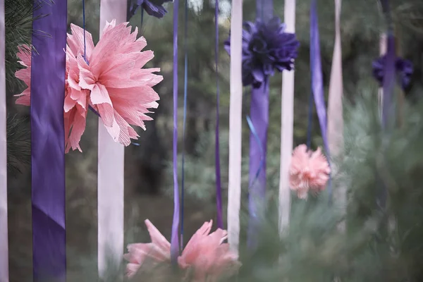 Pink flower with ribbons in a coniferous forest.