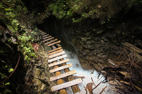 Dangerous trail through a waterfall with wooden ladders in the S