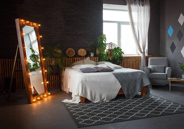 Stilvolles Loft gemütliches Wohnzimmer mit Doppelbett, Teppich, Sessel, grünen Pflanzen und geometrischen Mustern an der Wand — Stockfoto