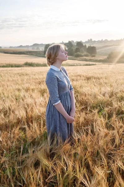 gün doğumunda kulakların altın alanda mavi eski moda açık elbise güzel mutlu genç kız. Arka planda sisli şafak.