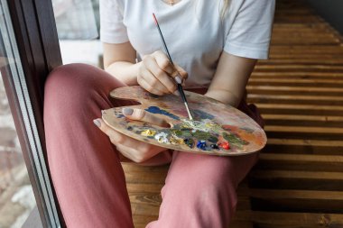 Palet yakın yukarı fırça karıştırma renkleri ile sanatçı elleri. Sanat, yaratıcılık, hobi.