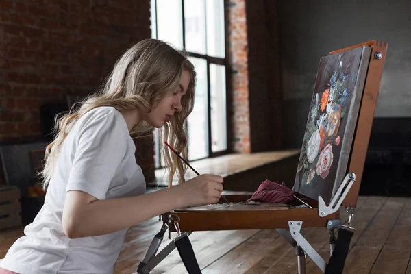 Fırça ile genç güzel kız ve palet resim çizim yakınında oturuyor. Sanat, yaratıcılık, hobi, çizim süreci.