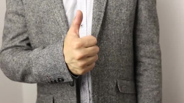 Solidní Kavkazan v šedé bundě a skvrnité košili na bílém pozadí si to s palcem rozjíždí. gesto pro dobré zaměstnání — Stock video