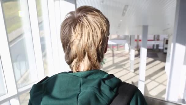 Closeup på unge blonde mænd tilbage kommer ned på rulletrappen på solskinsdag. Mand med rygsæk nedkørsler fra metro – Stock-video