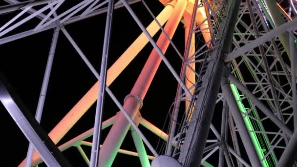 Detailní záběr na pomalu rotující mechanismus barevného mihotavého duhového ruského kola v zábavním parku v noci — Stock video