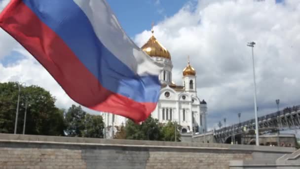 Bendera Rusia berkibar-kibar terhadap latar belakang Katedral Kristus Juruselamat di Moskow — Stok Video