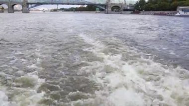 powerboat moving with full speed drive. view from stern of ship with water foam and surface behind. Motor boat floating on Moscow river. bridge on horizon in distance