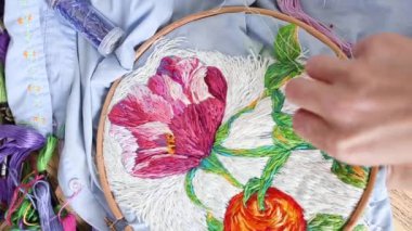 Vitiligo iğneli kadın elleri. Nakışlı halka, mavi işlemeli kumaş renkli desenli. Düz yatış, üst manzara, yakın çekim. Geleneksel hobi, yaşam tarzı. İğne işi, el işi.