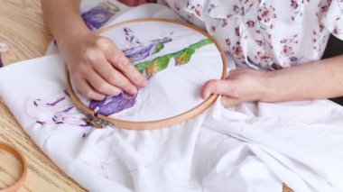 Vitiligo iğneli kadın elleri. Nakışlı halka, renkli desenli nakışlı kumaş. Üst Manzara, kapat. Geleneksel hobi, yaşam tarzı. İğne işi, el işi.