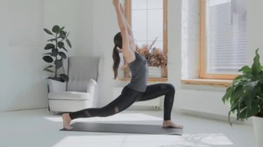 Gri saçlı, atkuyruklu esmer, genç bir kız. Siyah taytlar parlak odada paspas üzerinde egzersiz yapıyor. Evde spor ve spor eğitimi alıyorum. Sağlıklı bir yaşam tarzı. Uzanıyor, öne eğiliyor.