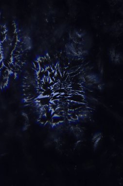 weird abstract backlit ice patterns on frozen glass with bizarre lines, curves, cracks, spots. blue texture wallpaper