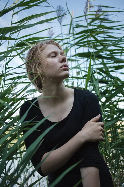 Portrait de jeune fille en robe noire avec de longs cheveux blonds mouillés posant à l'extérieur — Photo