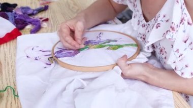 Vitiligo iğneli kadın elleri. Nakışlı halka, renkli desenli nakışlı kumaş. Üst Manzara, kapat. Geleneksel hobi, yaşam tarzı. İğne işi, el işi.