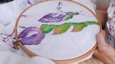 Vitiligo iğneli kadın elleri. Nakışlı halka, renkli desenli nakışlı kumaş. Üst Manzara, kapat. Geleneksel hobi, yaşam tarzı. İğne işi, el işi.