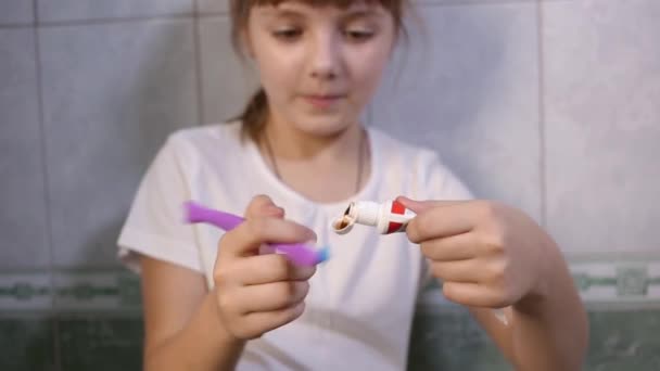 身穿白色T恤衫的8岁小女孩用刷子挤出牙膏 准备刷牙 儿童概念 防止蛀牙 上午或晚上在浴室的日常活动 — 图库视频影像