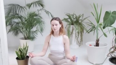 Spor kıyafetleri giyen bir kız Lotus pozisyonunda oturur. Gözleri kapalı, meditasyondan zevk alır.