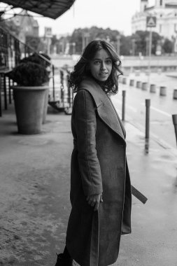 Siyah beyaz portre, gülümseyen, ceketli, balıkçı yakalı güzel bir kız. Çekici bir kadının sokak fotoğrafı, zarif bir modelin şehir fotoğrafı.