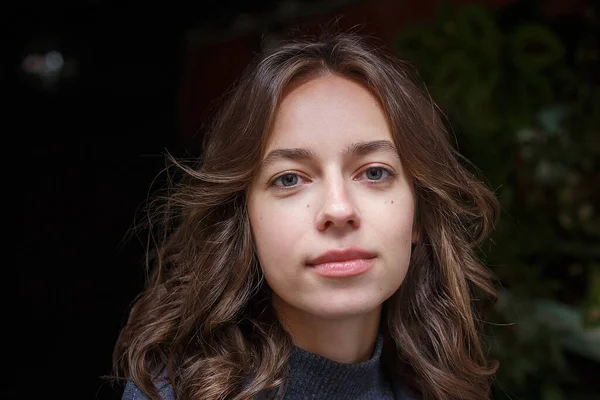 Açık havada poz veren gülümseyen mutlu genç kızın yüzüne yakın çekim. Çekici bir kadının sokak fotoğrafı, zarif bir modelin şehir fotoğrafı, yakın çekim.