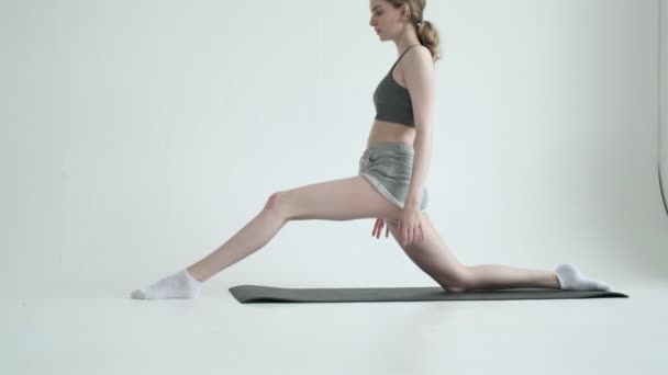 Ung vältränad flicka gör splitter motion i ljusa rummet. pilates, konditionsträning — Stockvideo