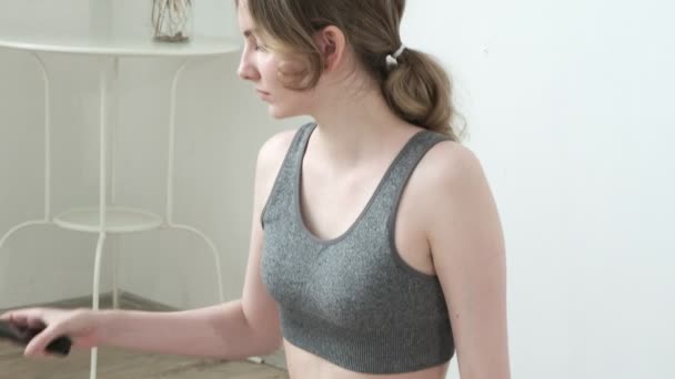 Jong fit mooi meisje dragen sportkleding zit in lotus poseren mediteren thuis — Stockvideo