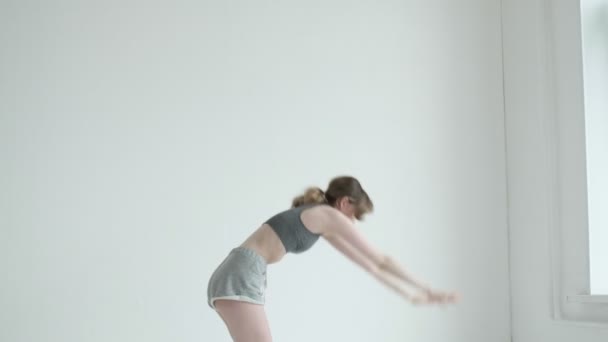 Jeune fille mince fit fait des exercices de yoga dans une pièce lumineuse. sport, entraînement physique — Video