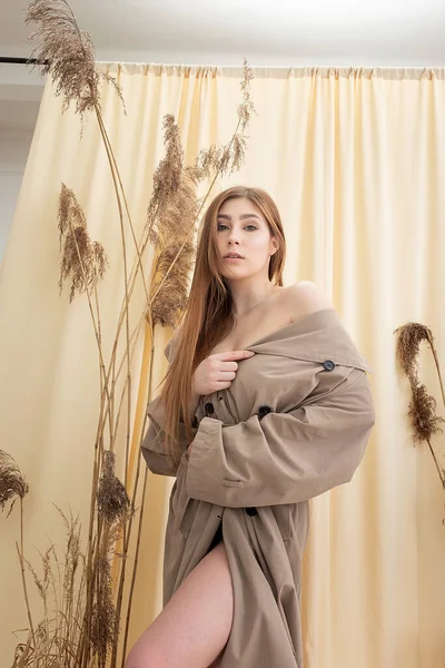 Pretty woman in beige raincoat on pastel fabric background. fashion photo shoot — Stock Photo, Image