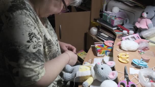 Kobieta w okularach dzianiny kapelusz dla słodkie zabawki myszy, co samodzielnie pamiątka w domu — Wideo stockowe