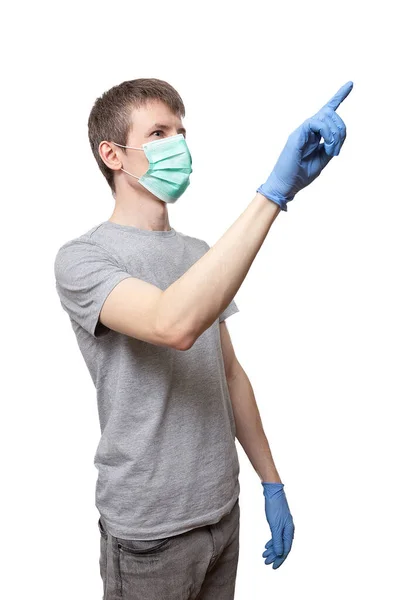 Mavi eldivenli adam, koruyucu ilaç maskesi parmağıyla işaret ediyor.
