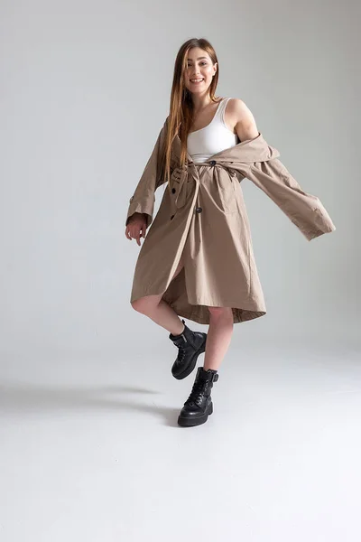 Atraente caucasiano magro menina em capa de chuva posando no branco estúdio cyclorama — Fotografia de Stock