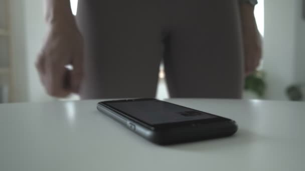 Onherkenbaar fit jong meisje in leggings raakt scherm van smartphone, close-up — Stockvideo
