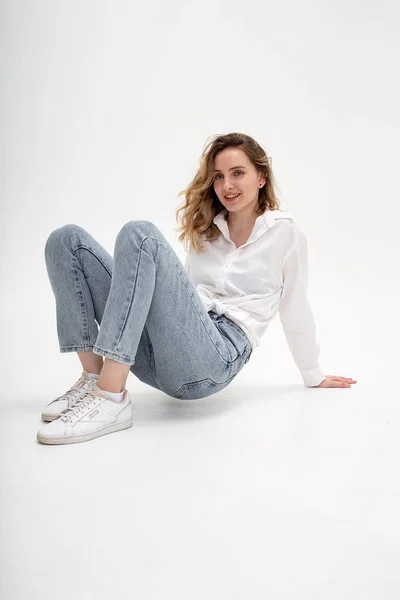 Junges, nachdenkliches kaukasisches Mädchen posiert in weißem Hemd, blauer Jeans im Studio — Stockfoto