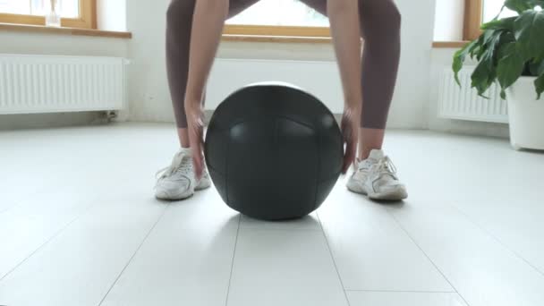 Fiatal kaukázusi barna nő emelő nehéz labdát otthon, fitness gyakorlatok — Stock videók