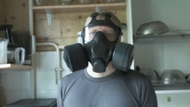 Человек в противогазе сидит дома на кухне. химическое оружие, защита от вирусов — стоковое видео
