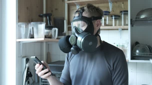 Nervøs mand i gasmaske taler smartphone i køkkenet derhjemme. virusbeskyttelse – Stock-video