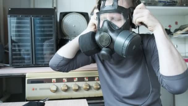 Een man met een gasmasker luistert naar muziek in een koptelefoon, schudt het hoofd. epidemie thuis — Stockvideo